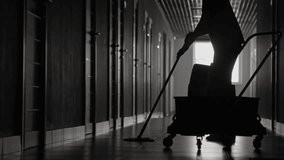 Cropped shot of figure cleaning floors with mop in dark hallway, showing only hands and lower body in a dimly lit environment. - Powered by Shutterstock - Get 15% off with code: PIKWIZARD15
