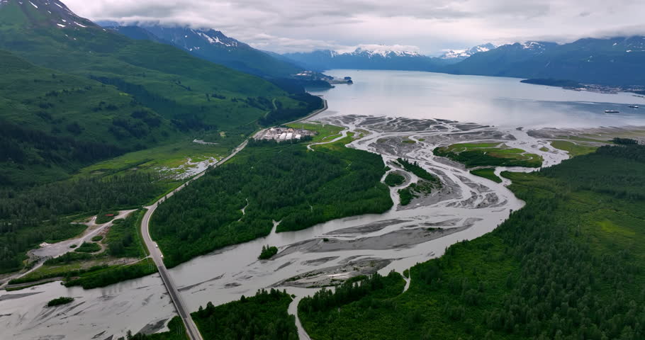 Branching river flows into a vast waterscape. Beautiful scenery of wild nature in Alaska, USA. Verdant mountains at backdrop. Aerial view.