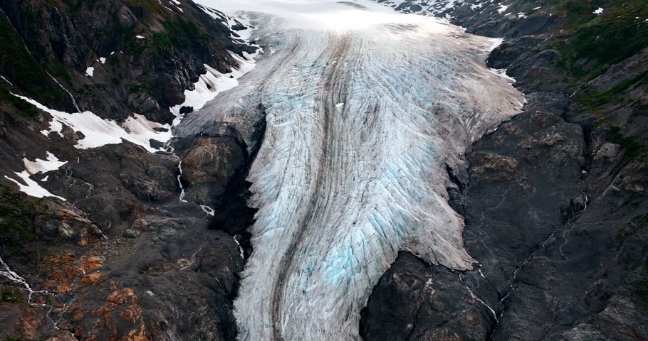 Beautiful old glacier in the rocks of Alaska, USA. Ridged layer of ice covering the mountain. Aerial view.