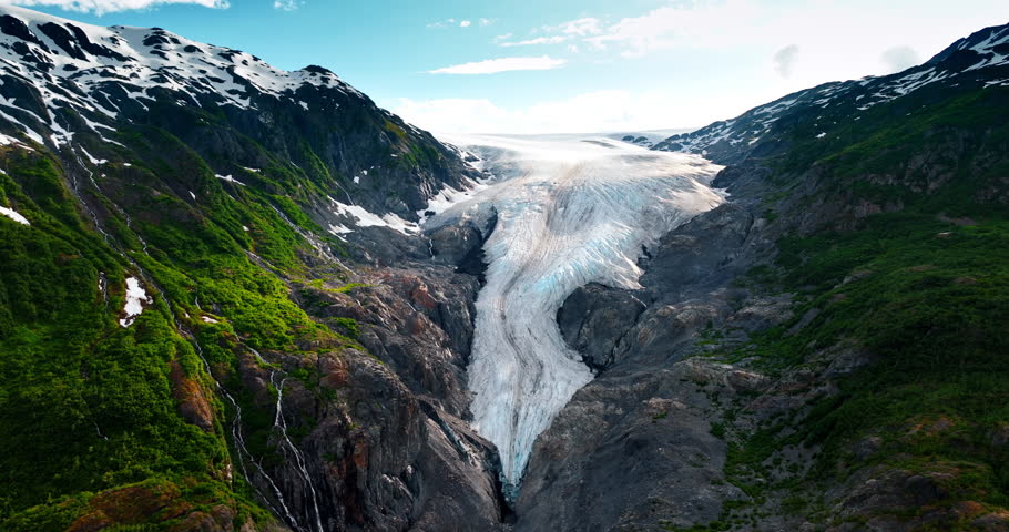 Snow and greenery cover the rocks. Approaching the iceberg covering the mountain in Alaska, USA.