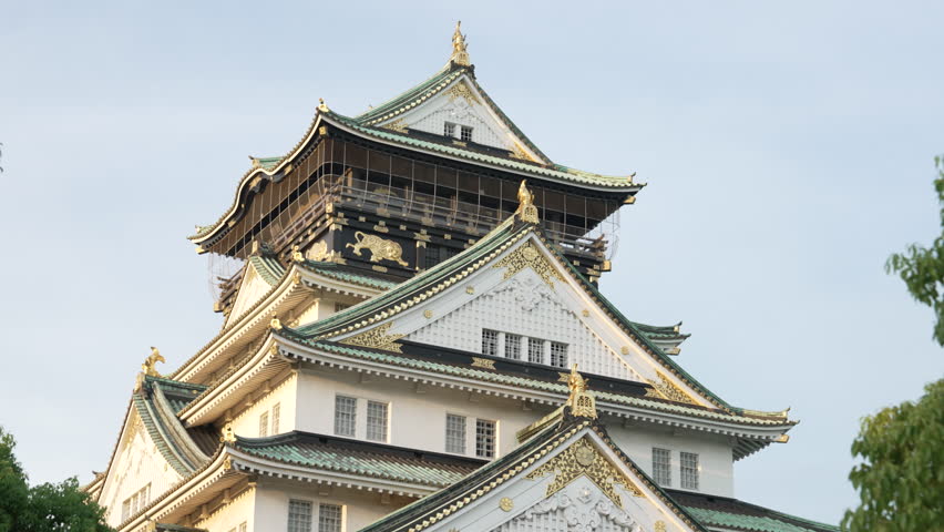 4k establishing shot of Osaka castle during bright sunset.