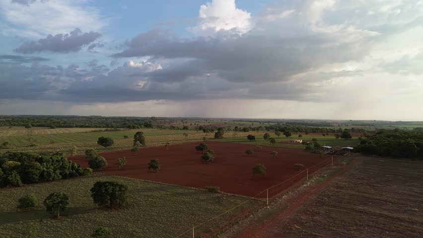 Dramatic farmland, red soil, and rainbow emergence.
