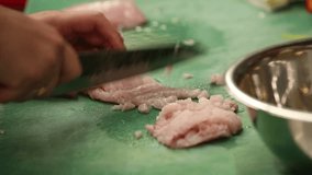 A professional chef meticulously dices raw fish fillets on a vibrant green cutting board in a commercial kitchen. This close-up highlights precise food preparation for healthy, delicious meals. - Powered by Shutterstock - Get 15% off with code: PIKWIZARD15
