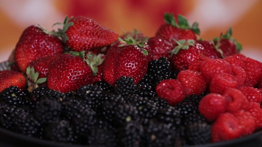 Close-up shot of a vibrant platter of fresh, ripe mixed berries. Features juicy strawberries, plump raspberries, and dark blackberries, perfect for a healthy snack or dessert. Delicious and nutritious