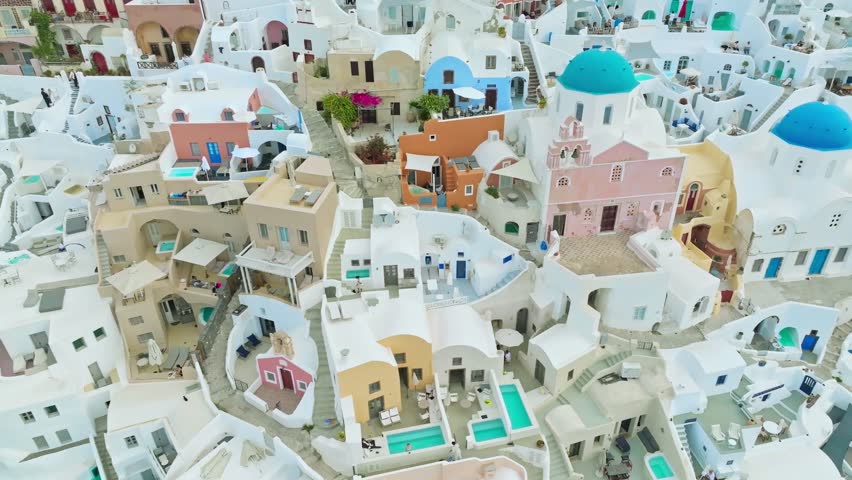 Breathtaking aerial view of Santorini, Greece, showcasing the iconic whitewashed buildings, blue domes, and dramatic caldera views against the Aegean Sea.