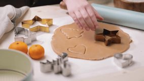 Person uses a cookie cutter to shape cookies from rolled-out dough, preparing for holiday baking. - Powered by Shutterstock - Get 15% off with code: PIKWIZARD15