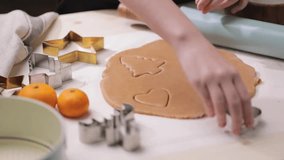 Person uses a cookie cutter to shape cookies from rolled-out dough, preparing for holiday baking. - Powered by Shutterstock - Get 15% off with code: PIKWIZARD15