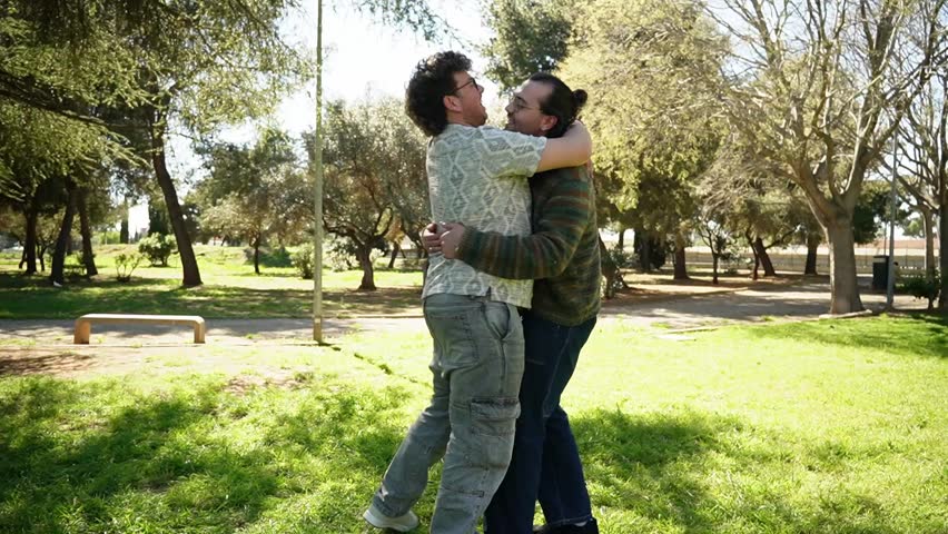 Young male couple sharing an intimate and loving moment hugging and kissing each other in a park