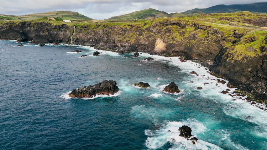 Volcanic sea cliffs eroded by waves, with grass-covered plateaus on top, Azores archipelago