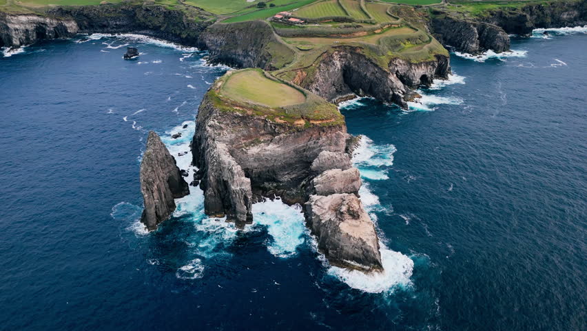 Aerial panorama of rocky headland surrounded by deep blue Atlantic waters, Sao Miguel Island, Azores