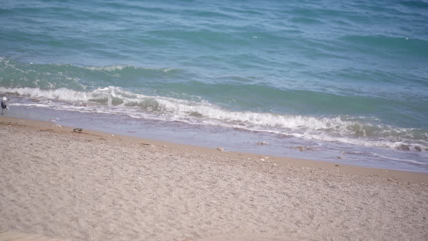 The sea waves gently wash over the empty sandy beach.