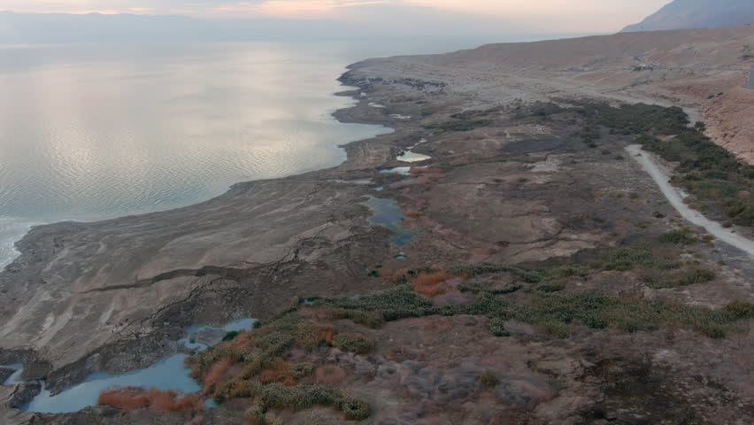 Drone view Dead Sea sinkholes landscape

Aerial footage showing dramatic sinkholes and drying shoreline along the Dead Sea, Israel, during sunset.
