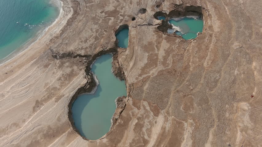 Drone view Dead Sea sinkholes landscape

Aerial footage showing dramatic sinkholes and drying shoreline along the Dead Sea, Israel, during sunset.
