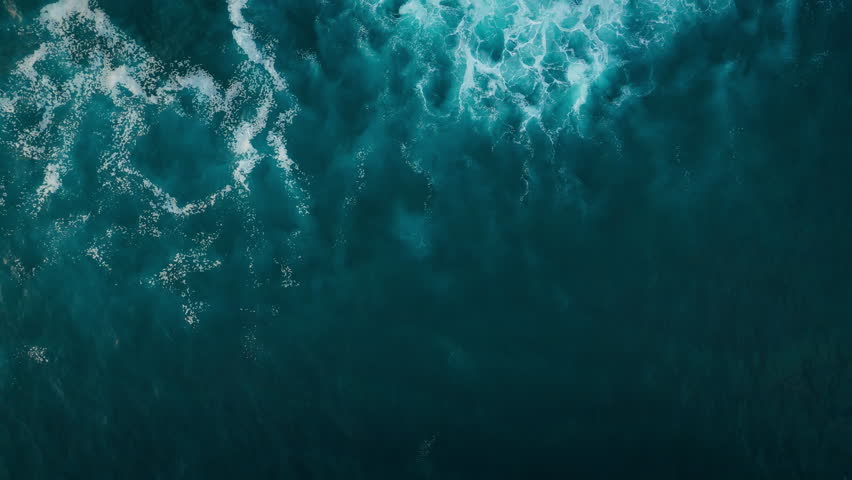 Aerial top down view of Atlantic oceanic waves rolling and creating foam patterns, Drone filming breaking surf with foam in Atlantic ocean