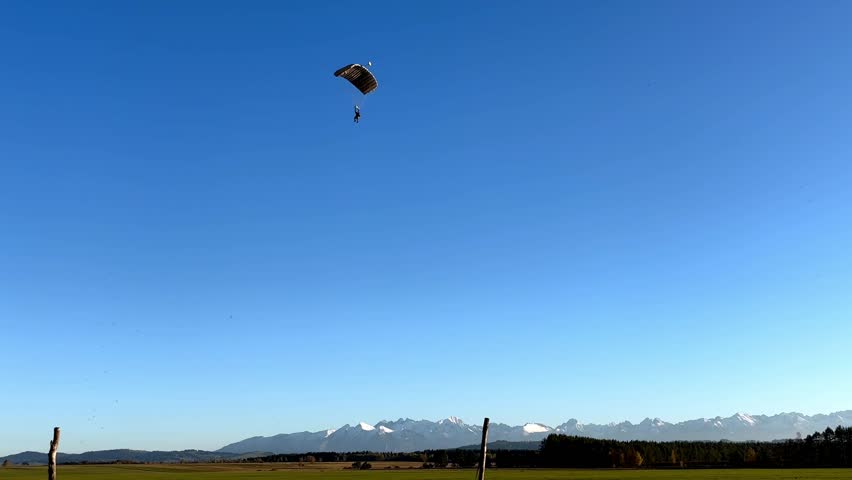 A parachutist landing against a backdrop of mountains