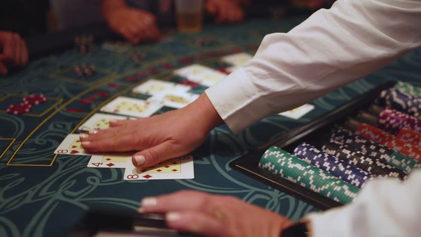 Casino table with roulette wheel in motion, with casino chips, tokens, the hand of croupier, dollar money and a group of gambling rich people playing bet on a party, blue poker table and deck of cards