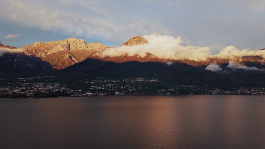 Village and mountain landscape along the shores of Lake Como, Lombardy, Italy. Mountains rise above the villages of Mandello del lario, Crebbio and Borbona, clouds float over the houses.