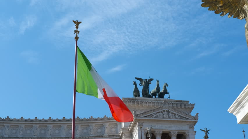 Italian flag waving atop vittoriano monument in rome. National flag of italy fluttering in the wind on a sunny day in front of the altar of the fatherland, a patriotic symbol of the italian republic