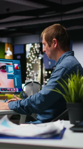 Vertical Video Male graphic designer using AI powered content for image retouching, working on contrast adjustments. Photographer employs futuristic interface for his portfolio, artificial