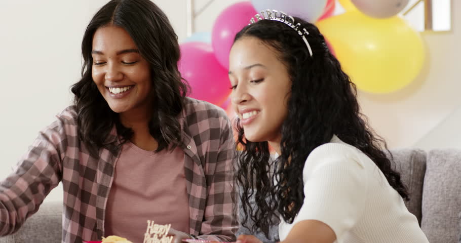 Diverse female friends celebrating 18th birthday in living room, showing red velvet cake and snacks. Party, milestone, teenage, vibrant, cheerful, confection, snacking
