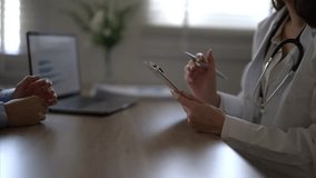 A doctor is talking to a patient in a medical office. The patient is holding a clipboard and the doctor is holding a pen - Powered by Shutterstock - Get 15% off with code: PIKWIZARD15