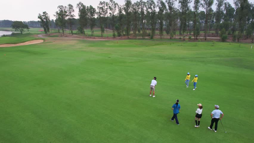Drone view of young pro golfers swings the club on scenic golf course. Attractive athletes enjoy outdoor recreation with light exercise and sport lifestyle while playing golf at course ground together