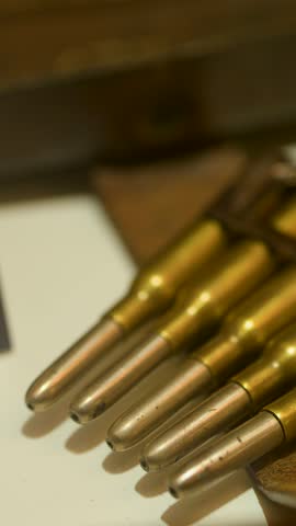 Detailed macro view of historical rifle cartridges in a museum, warm lighting, slow camera pan