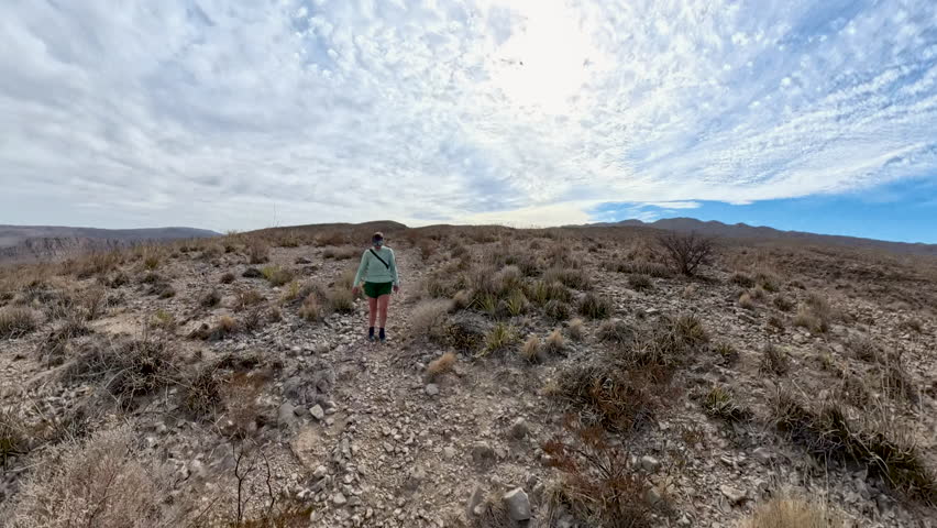 Woman Hikes on Gravel Trail Over Desert Hill in Big Bend