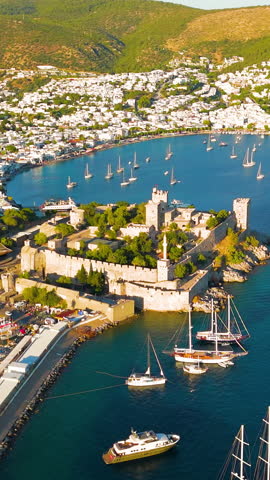 Vertical video. Bodrum, Turkey. Aerial drone panorama of Bodrum Castle dominating coastline with yachts in bay, beaches and white houses scattered on hills. Aerial View, MasterShots, Circle (Far). Ri