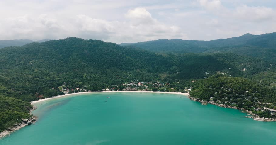 A wide bay with turquoise waters and a shoreline surrounded by lush green hills and tropical forest. Thong Nai Pan Yai Beach. Ko Pha Ngan, Thailand.