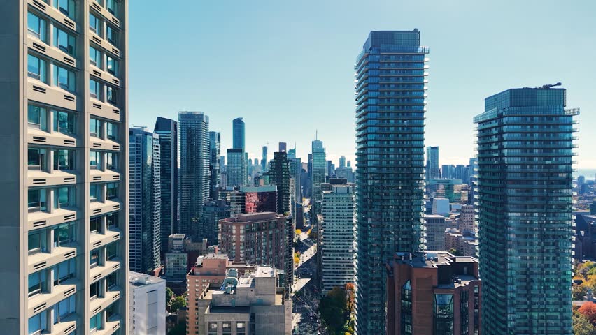 Spectacular panoramic drone view of modern Downtown skyscrapers and Lake Ontario against blue sky in Toronto, Ontario, Canada.