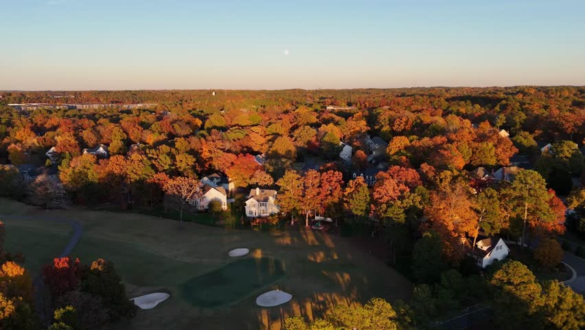 Autumn drone view of countryside houses among colorful trees, USA.