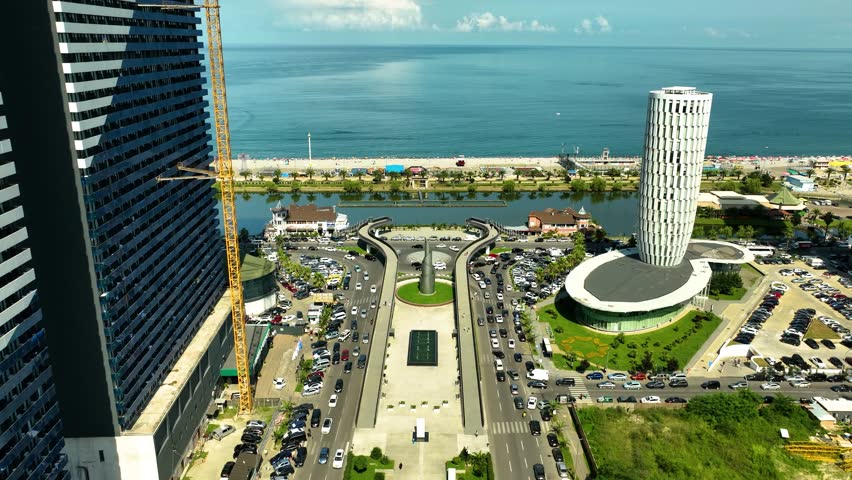 Aerial view of Batumi’s seaside boulevard with modern buildings, traffic, and the Black Sea in the background.