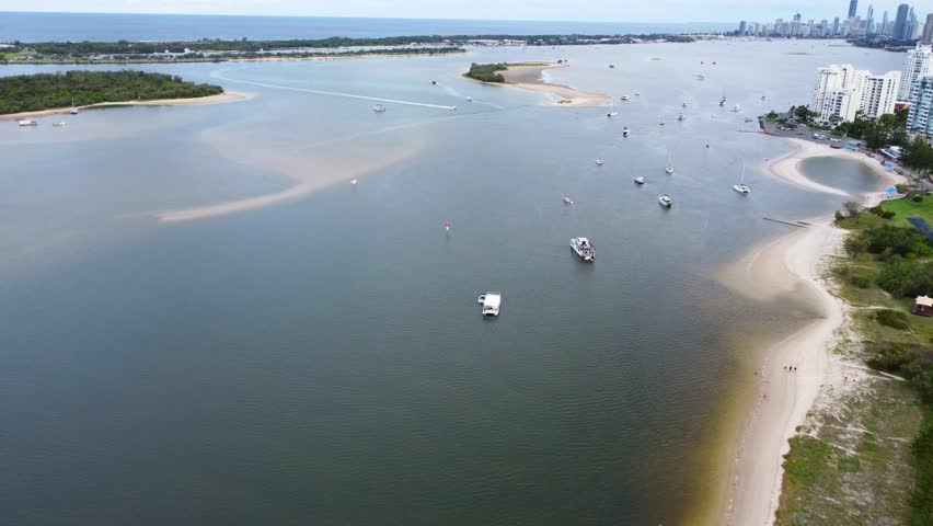 Aerial drone view of the Gold Coast Broadwater in Queensland, Australia, showing boats, sandbanks, and the city skyline under a cloudy sky.