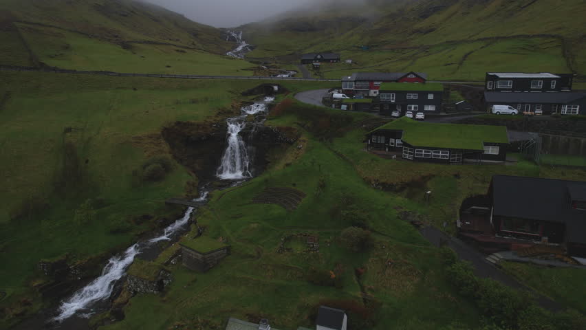 Stunning aerial view of a traditional village with turf roof houses and waterfalls in Faroe Islands