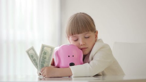Little girl sitting with a piggy bank and falls asleep
