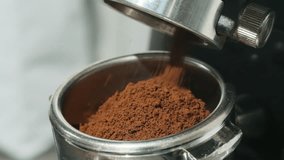 Professional barista transfers ground coffee into metal portafilter with espresso machine dispensing coffee powder in delicate stream slow motion - Powered by Shutterstock - Get 15% off with code: PIKWIZARD15