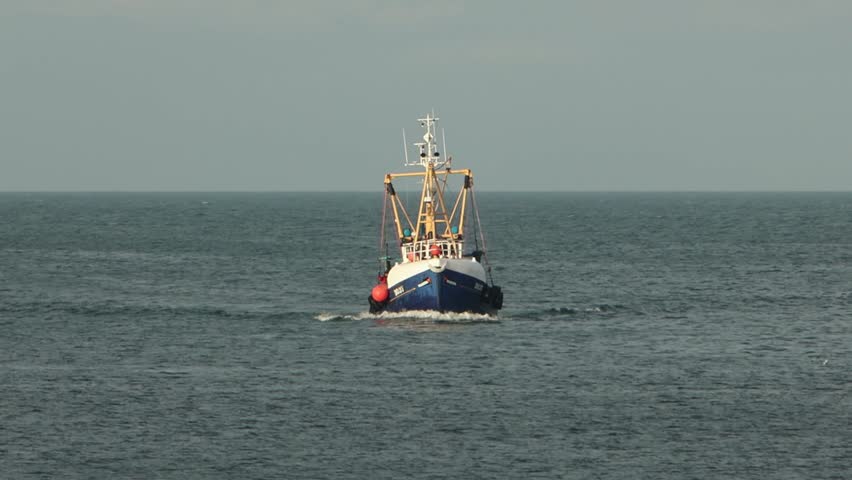 A small fishing boat coming in to shore after a fishing trip. Peel. Isle of Man. UK. Winter