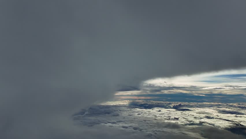 An immersive pilot’s perspective from the cockpit of a jet while flying near the top on a massive and threatening cumulonimbus storm cloud. 4K aerial shot.
