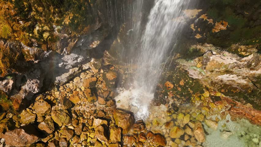 Clear mountain waterfall flowing over mossy rocks into a turquoise pool in Albania. Peaceful and natural landscape perfect for travel or nature footage.