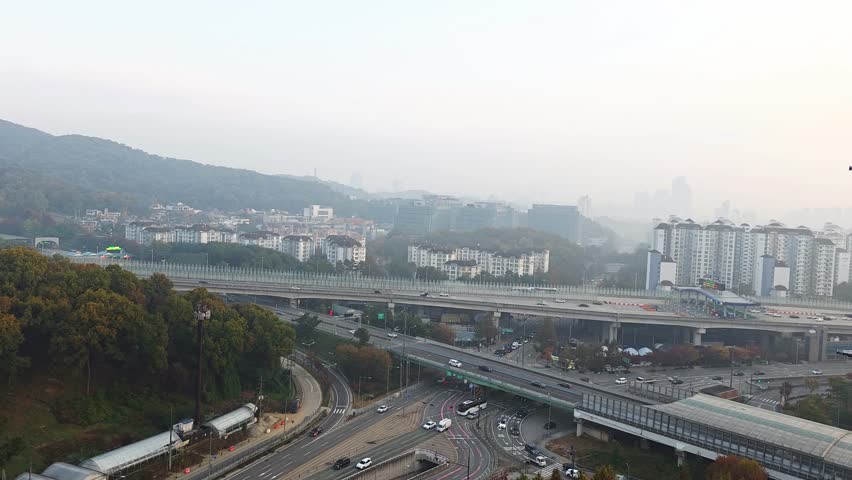 Aerial view capturing busy traffic flow on Umyeongsan-ro highway passing through the Seongnam Toll Gate towards the Seocho tunnel on a hazy autumn day in South Korea