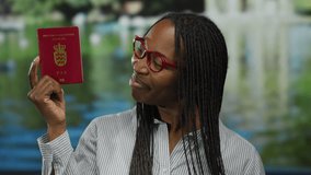 Woman holding danish passport smiles by outdoor lake setting, showcasing nationality and travel theme with vibrant energy. - Powered by Shutterstock - Get 15% off with code: PIKWIZARD15