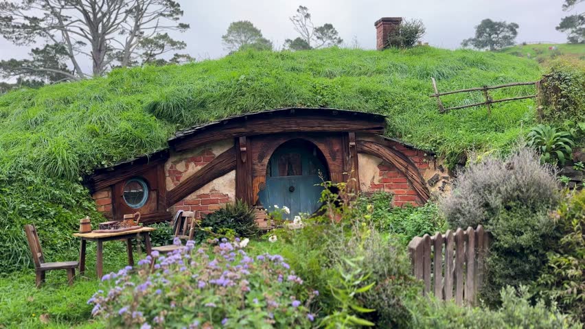A view of a charming Hobbit home at Hobbiton in New Zealand. Surrounded by lush greenery and rolling hills, this iconic movie set creates a magical and scenic scene.
