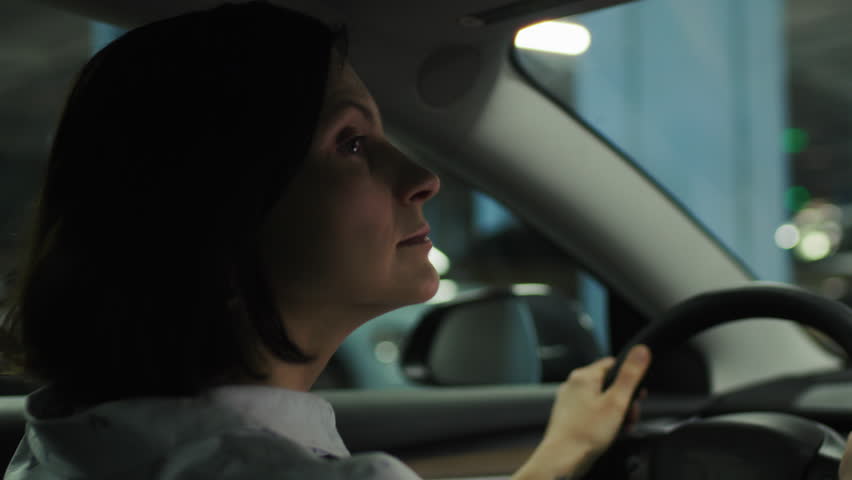 Woman Driving in Dark Parking Lot Searching for Parking Spot