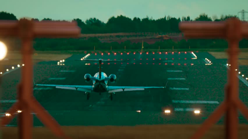 Private business jet landing on runway in evening with crosswind. Luxury aircraft touching down on landing strip with smoke rising from wheels during twilight conditions. Corporate jet arriving on