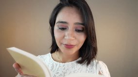 A South Asian woman in a white lace blouse smiling softly while reading a book, enjoying a peaceful indoor moment of reflection - Powered by Shutterstock - Get 15% off with code: PIKWIZARD15