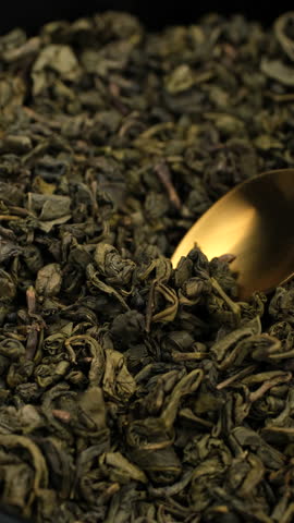 Dried green tea leaves scooping with spoon, close up. Process making tea drinks
