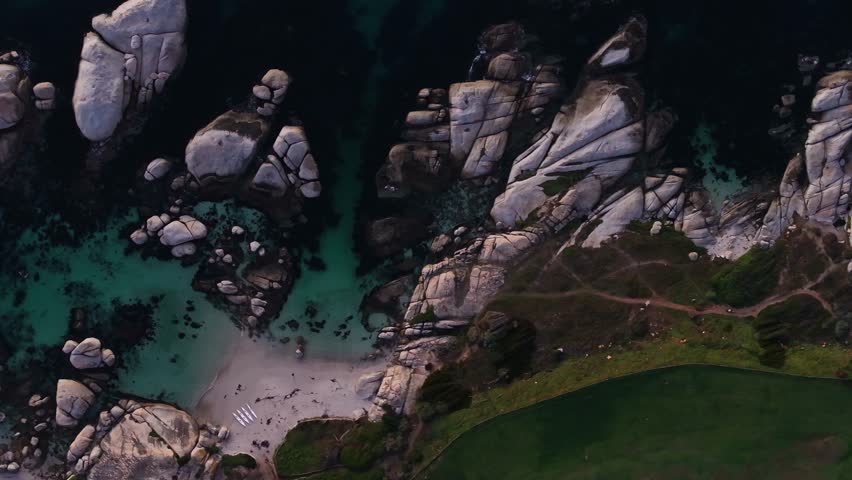 Aerial view of granite boulders contrast with turquoise waters and sandy beach, a beautiful coastal landscape, Cape Town, Western Cape, South Africa.
