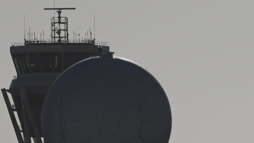 airplane flying past air traffic control tower at airport 