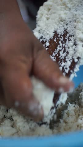 Close-up of a person manually grating cassava using a traditional grater, showing authentic Indonesian food preparation